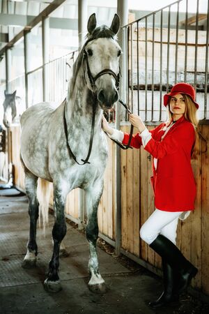 Young female rider with horse inside stable. equestrian sportの写真素材