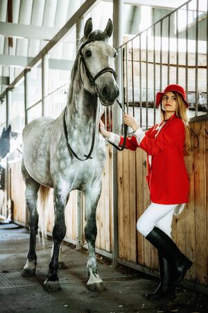 Young female rider with horse inside stable. equestrian sportの写真素材