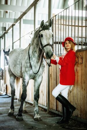Young female rider with horse inside stable. equestrian sportの写真素材