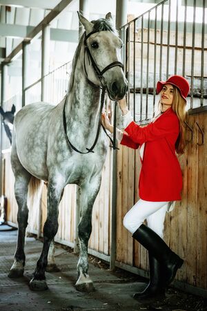 Young female rider with horse inside stable. equestrian sportの写真素材