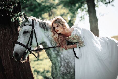 Beautiful and stunning bride, riding a horse in the nature, on her wedding dayの写真素材