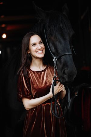 Wonderful lady with black horse in the stablesの写真素材