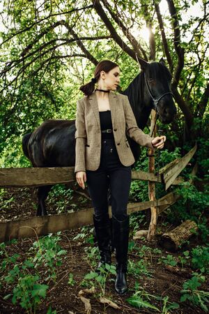 Fashionable portrait of a beautiful young woman and black horseの写真素材
