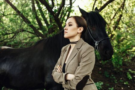 Fashion photoshoot of beautiful woman and black horse. Outdoor shot, sport and fashion concept.の写真素材