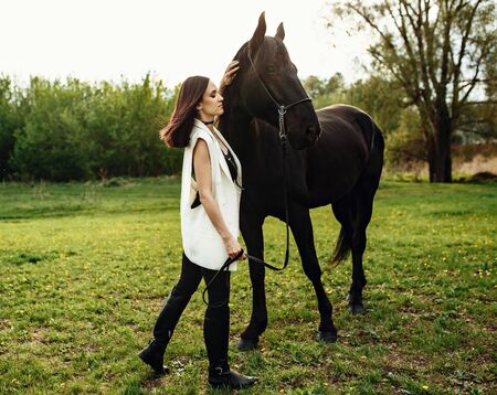 Fashion photoshoot of beautiful woman and black horse. Outdoor shot, sport and fashion concept.の写真素材
