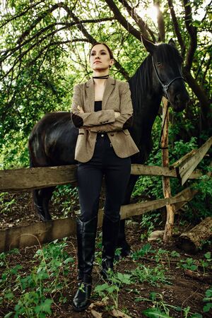 Fashionable portrait of a beautiful young woman and black horseの写真素材