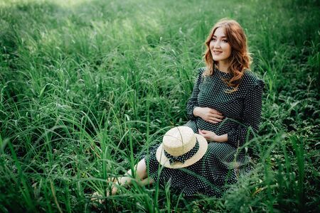 Pregnant woman posing in a green park. young happy pregnant woman relaxing and enjoying life in natureの写真素材