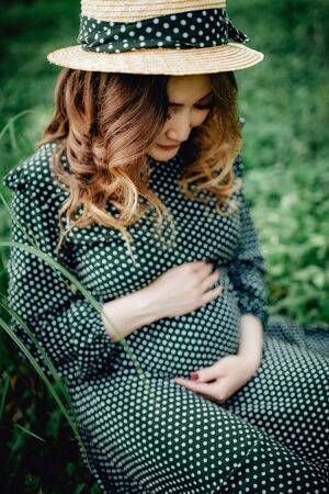 Pregnant woman posing in a green park. young happy pregnant woman relaxing and enjoying life in natureの写真素材