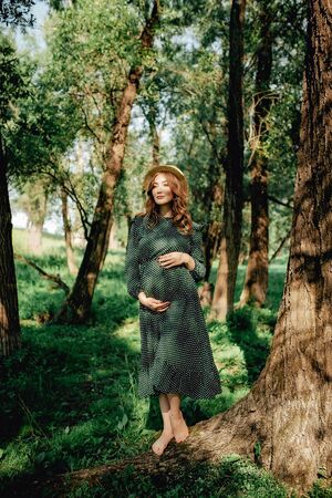 Pregnant woman posing in a green park. young happy pregnant woman relaxing and enjoying life in natureの写真素材