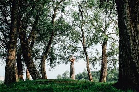 Pregnant woman posing in a green park. young happy pregnant woman relaxing and enjoying life in natureの写真素材