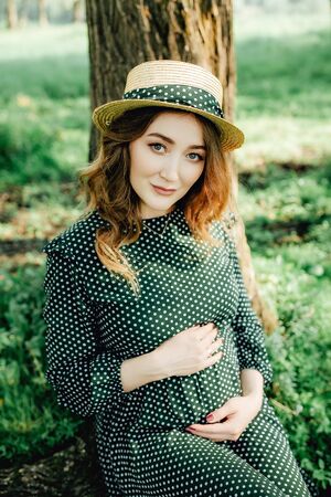 Young pregnant woman relaxing in park outdoors, healthy pregnancy.の写真素材