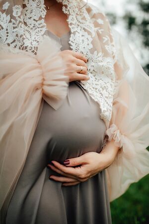 Close up of pregnant woman are relaxing in the garden at sunset. pregnant woman holding her belly and flower in the garden.の写真素材