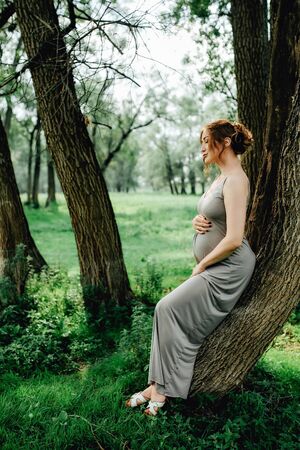 Young happy pregnant woman relaxing and enjoying life in nature. Outdoor shotの写真素材