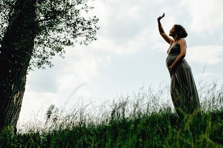 Pregnant woman posing in a green park. young happy pregnant woman relaxing and enjoying life in natureの写真素材