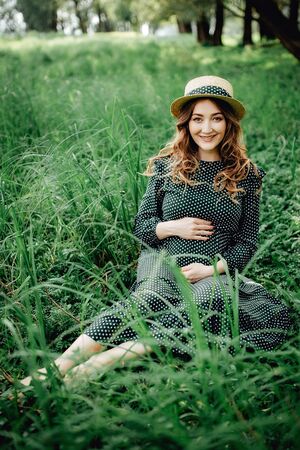 Pregnant woman posing in a green park. young happy pregnant woman relaxing and enjoying life in natureの写真素材