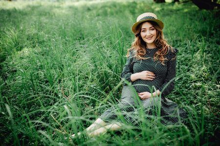 Young pregnant woman relaxing in park outdoors, healthy pregnancy.の写真素材