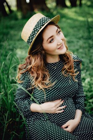 Young pregnant woman relaxing in park outdoors, healthy pregnancy.の写真素材