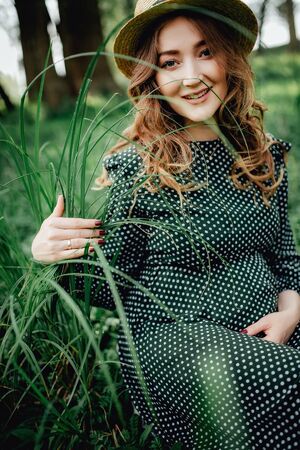 Pregnant woman posing in a green park. young happy pregnant woman relaxing and enjoying life in natureの写真素材