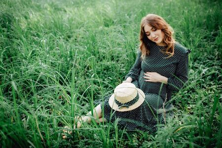 Pregnant woman posing in a green park. young happy pregnant woman relaxing and enjoying life in natureの写真素材