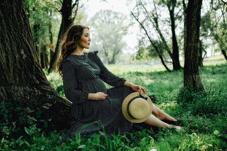 Young pregnant woman relaxing in park outdoors, healthy pregnancy.の写真素材
