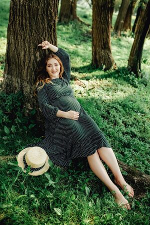 Young pregnant woman relaxing in park outdoors, healthy pregnancy.の写真素材