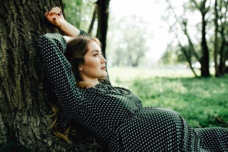 Young pregnant woman relaxing in park outdoors, healthy pregnancy.の写真素材