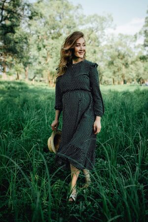 Pregnant woman posing in a green park. young happy pregnant woman relaxing and enjoying life in natureの写真素材