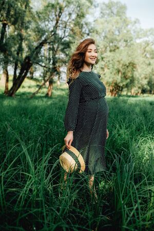 Pregnant woman posing in a green park. young happy pregnant woman relaxing and enjoying life in natureの写真素材