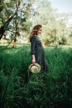 Pregnant woman posing in a green park. young happy pregnant woman relaxing and enjoying life in natureの写真素材