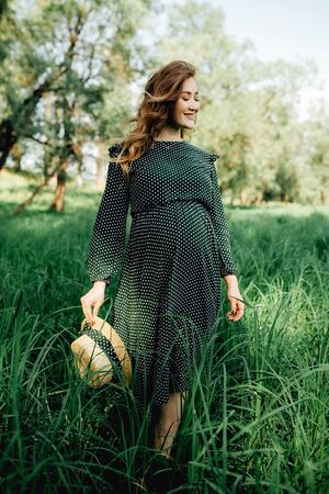 Pregnant woman posing in a green park. young happy pregnant woman relaxing and enjoying life in natureの写真素材