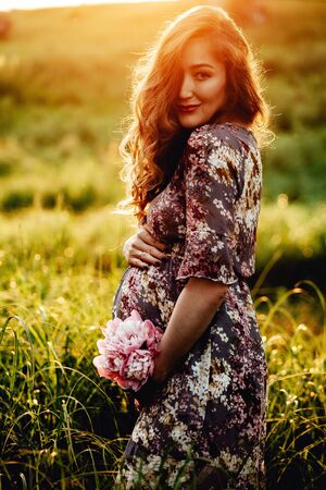 Portrait of beautiful pregnant woman in a green fieldの写真素材