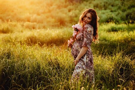 Portrait of beautiful pregnant woman in a green fieldの写真素材