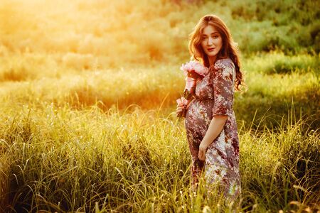 Portrait of beautiful pregnant woman in a green fieldの写真素材