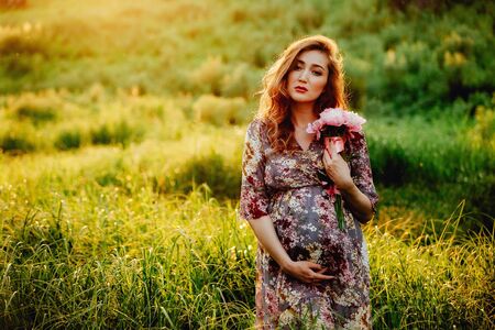 Portrait of beautiful pregnant woman in a green fieldの写真素材