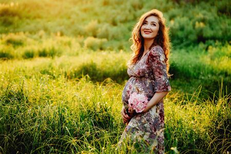 Portrait of beautiful pregnant woman in a green fieldの写真素材