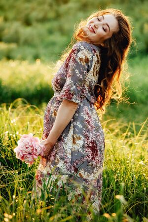 Portrait of beautiful pregnant woman in a green fieldの写真素材