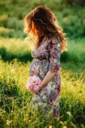 Portrait of beautiful pregnant woman in a green fieldの写真素材