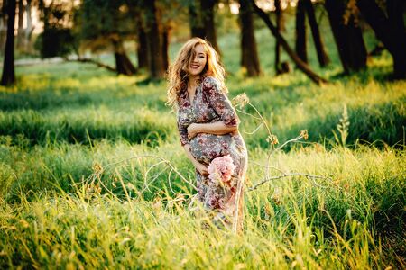 Portrait of beautiful pregnant woman in a green fieldの写真素材