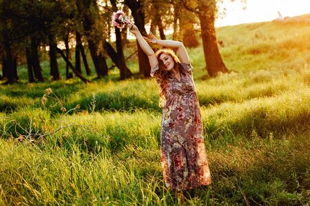 Pregnant woman feeling happy with new life at summer field while take care of her child. The young expecting mother holding baby in pregnant belly. Maternity prenatal care and woman pregnancy concept.の写真素材