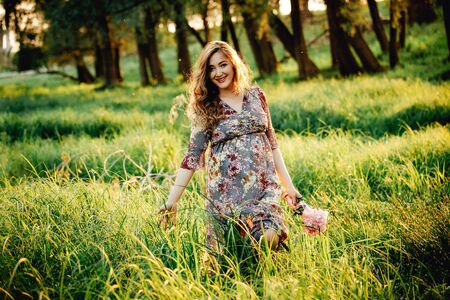 Portrait of beautiful pregnant woman in a green fieldの写真素材