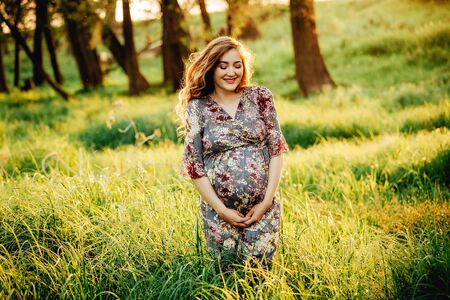 Portrait of beautiful pregnant woman in a green fieldの写真素材