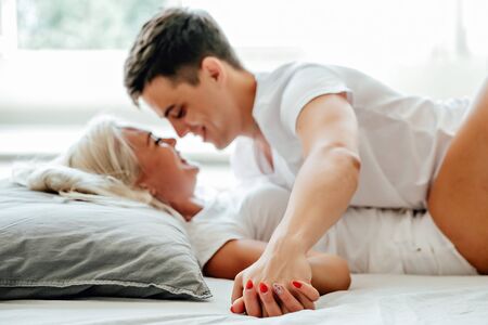 Beautiful passionate couple is having sex on bed in the morningの写真素材
