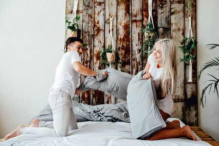 Happy young couple is having fun in bed. Enjoying the company of each other. Pillow battleの写真素材