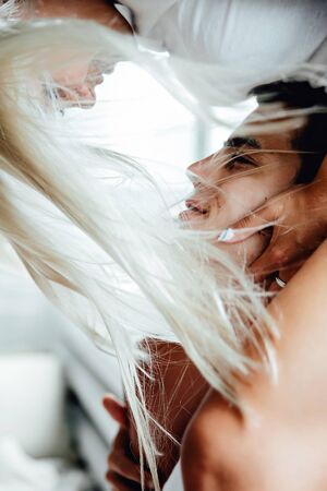 Portraiy of Young blond woman sits on Caucasian man's shoulders as they hold hands and look at each otherの写真素材