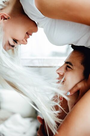 Portraiy of Young blond woman sits on Caucasian man's shoulders as they hold hands and look at each otherの写真素材