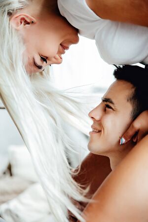 Portraiy of Young blond woman sits on Caucasian man's shoulders as they hold hands and look at each otherの写真素材
