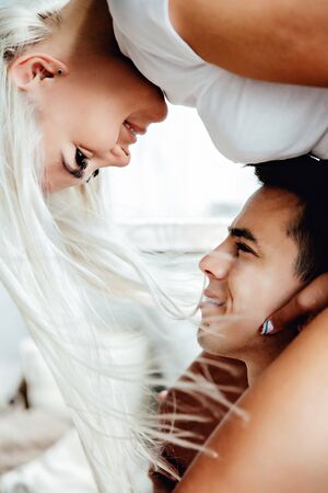 Portraiy of Young blond woman sits on Caucasian man's shoulders as they hold hands and look at each otherの写真素材
