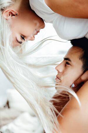 Portraiy of Young blond woman sits on Caucasian man's shoulders as they hold hands and look at each otherの写真素材
