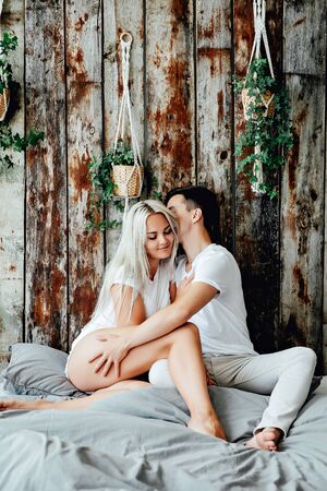 Portrait of romantic couple sitting on bed in bedroomの写真素材