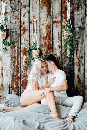 Portrait of happy couple sitting on bed at homeの写真素材